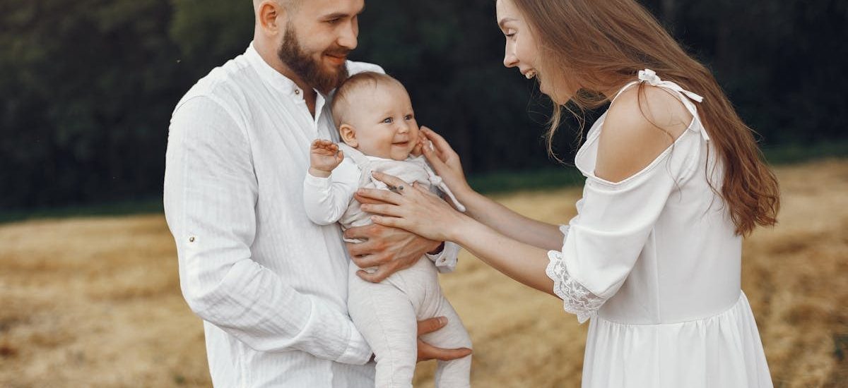 A joyful family moment captured outdoors with parents and a smiling baby.