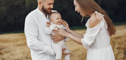 A joyful family moment captured outdoors with parents and a smiling baby.