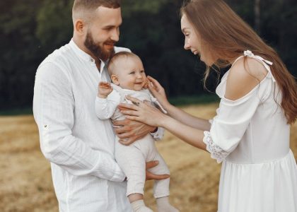 A joyful family moment captured outdoors with parents and a smiling baby.